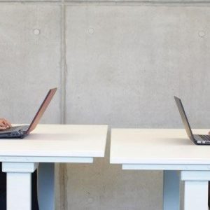 Male and female coworkers sitting across from each other while working on their laptops