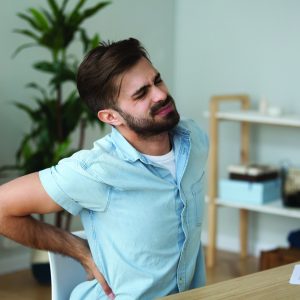 Tired man feeling pain in back suffering from lower backache