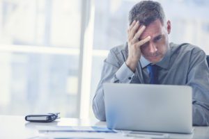 Stressed mature businessman with laptop.