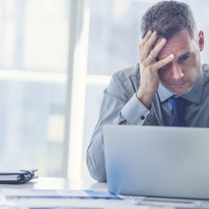 Stressed mature businessman with laptop.