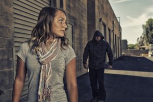 Woman being followed by a man with his hood up