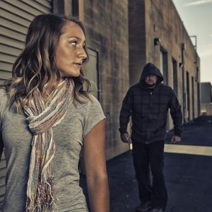 Woman being followed by a man with his hood up