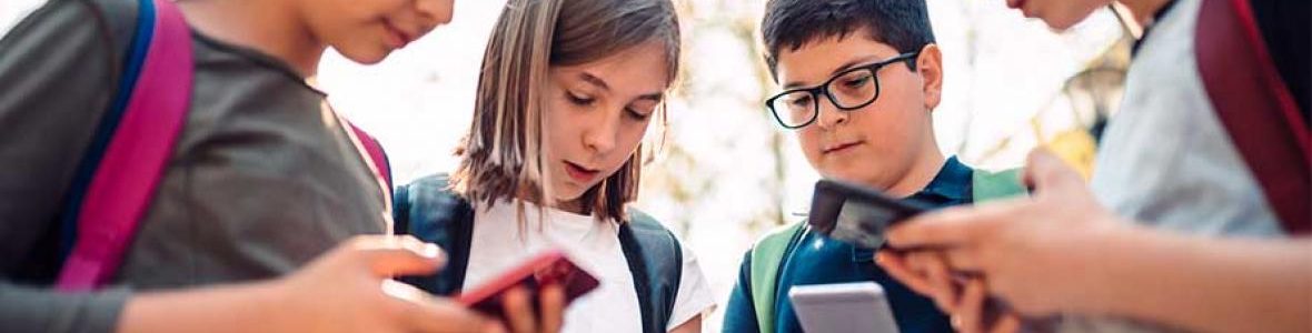 Huddle of children with backpacks and texting on their smartphones