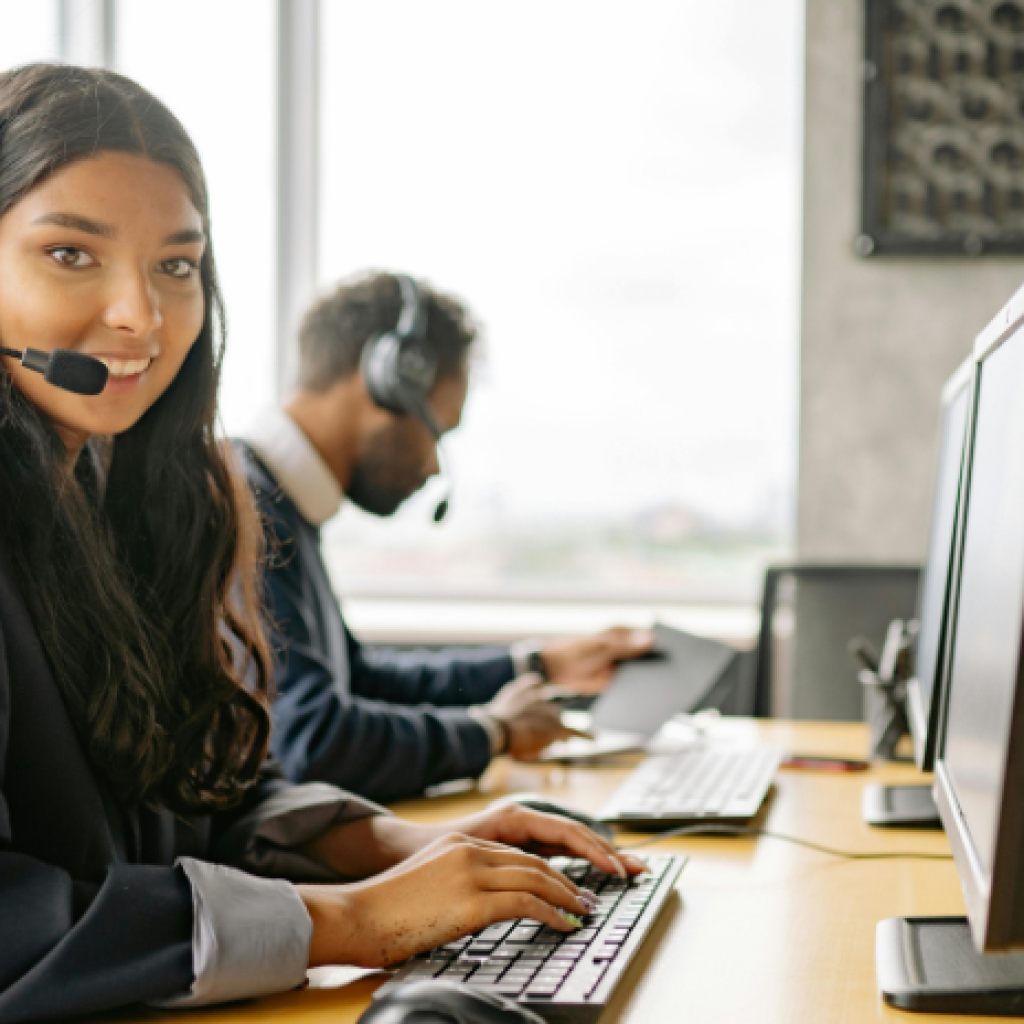 Two call center employees working at shared desk.