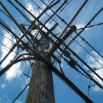 A view looking up at an electricity pylonm with a blue sky in the background