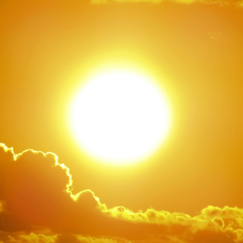 A picture of the sun shining bright orange above some cloud formations
