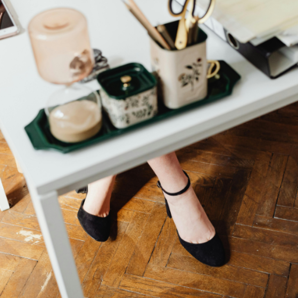 An office worker's feet in smart shoes beneath their desk