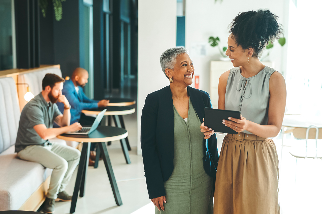 Vision, mission and success with a female leader, manager or CEO and an employee or young designer working on a tablet in a modern office. Leadership, technology and teamwork in a creative company