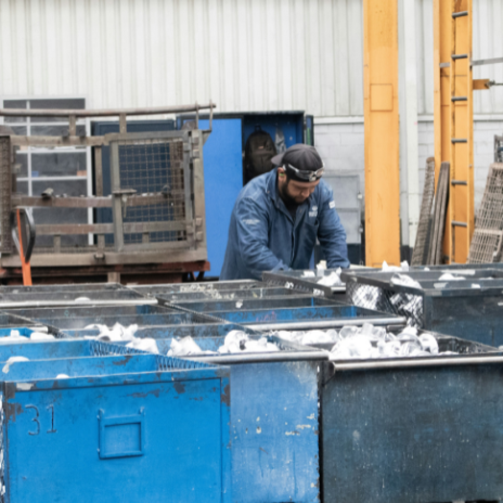 A worker at a manufacturing plant sorting through bins of waste materials