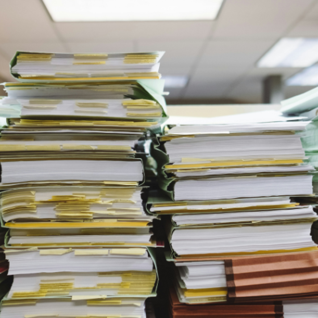 Paperwork stacked high in an office workspace