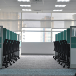 An office isle between two rows of ergonomic chairs and desks