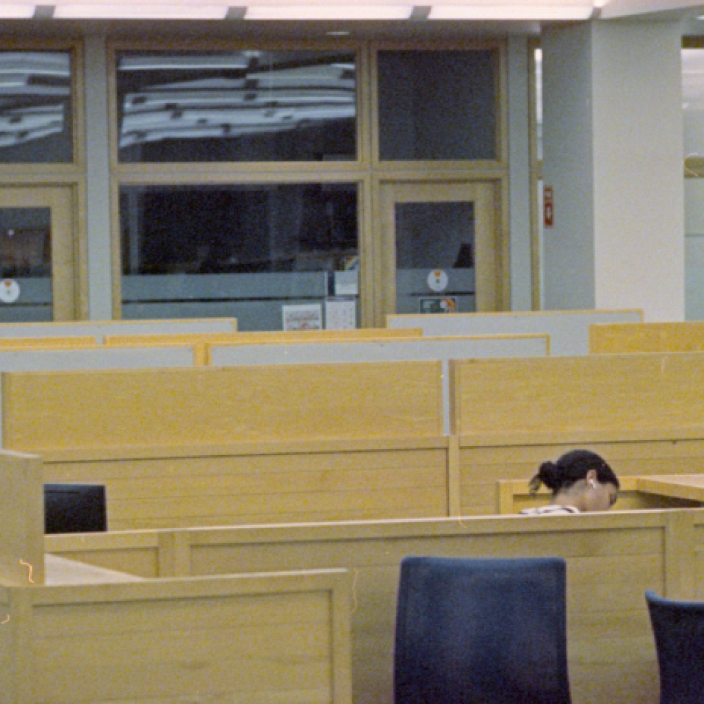 A lone office worker, barely visible above cubicle partitions.