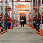 A warehouse worker seen from a distance carrying out a manual handling task.