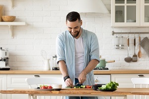 Man chopping food at the kitchen counter, eating for wellness