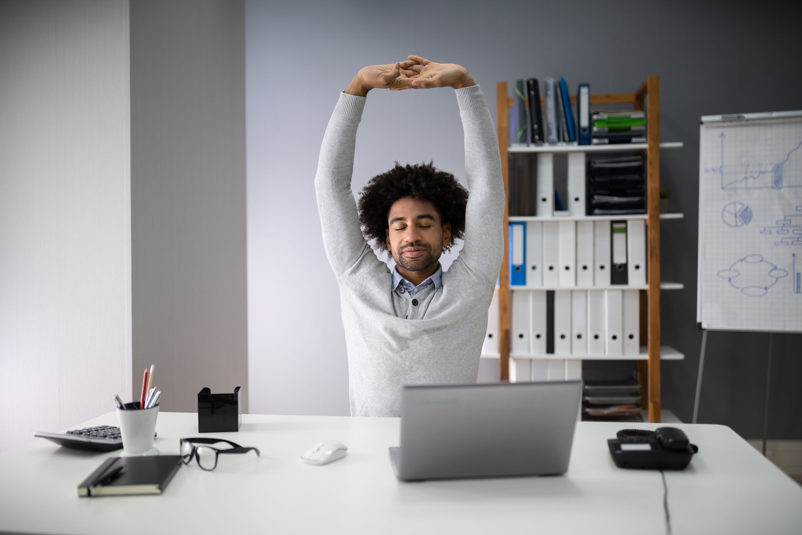 Self care plus image Man stretching at desk