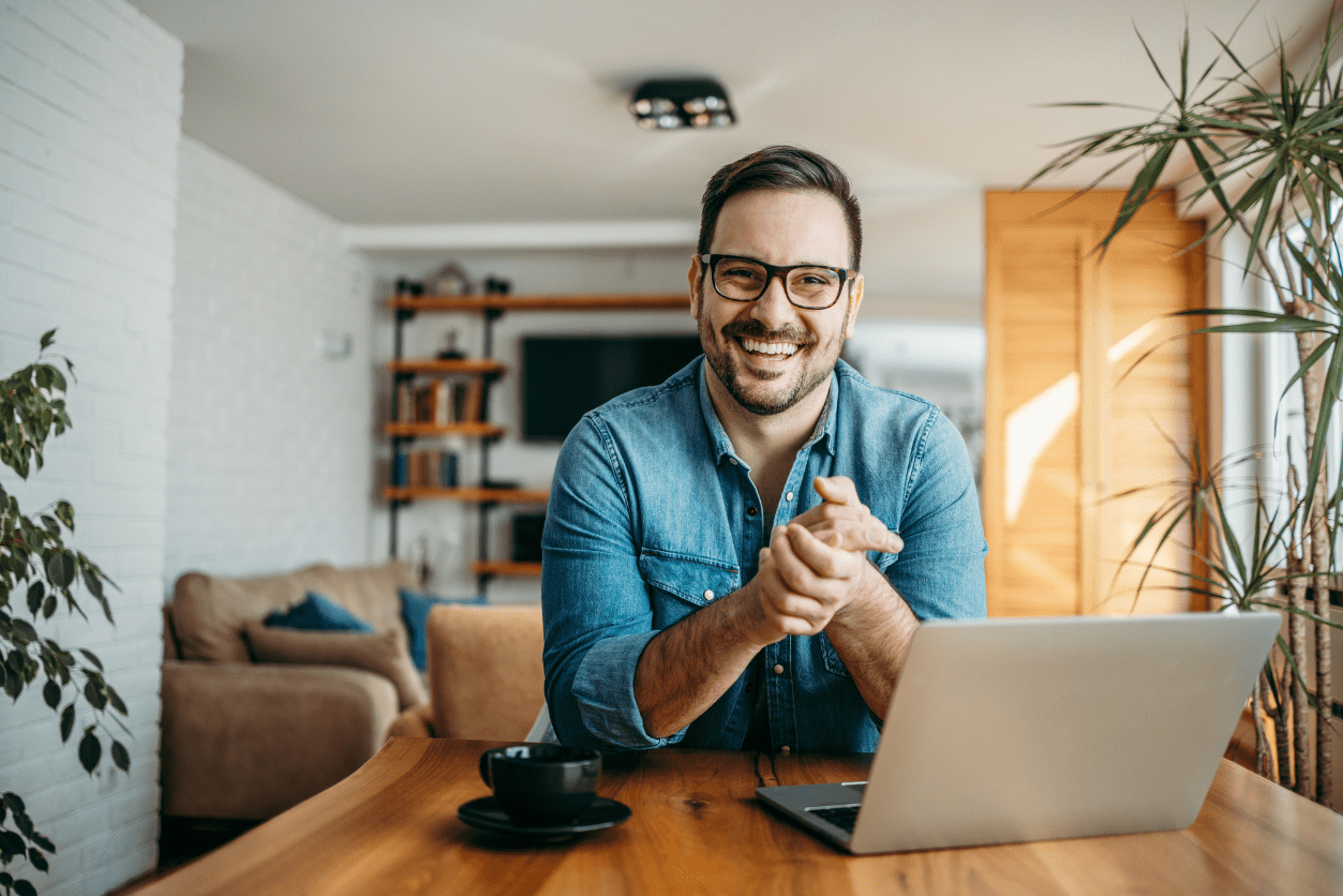 A joyful man working on a laptop at his desk