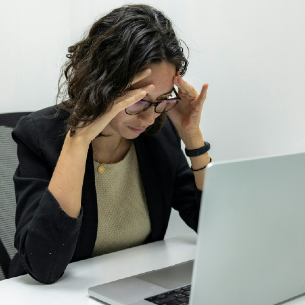 A worker with her hands to her head at her desk.
