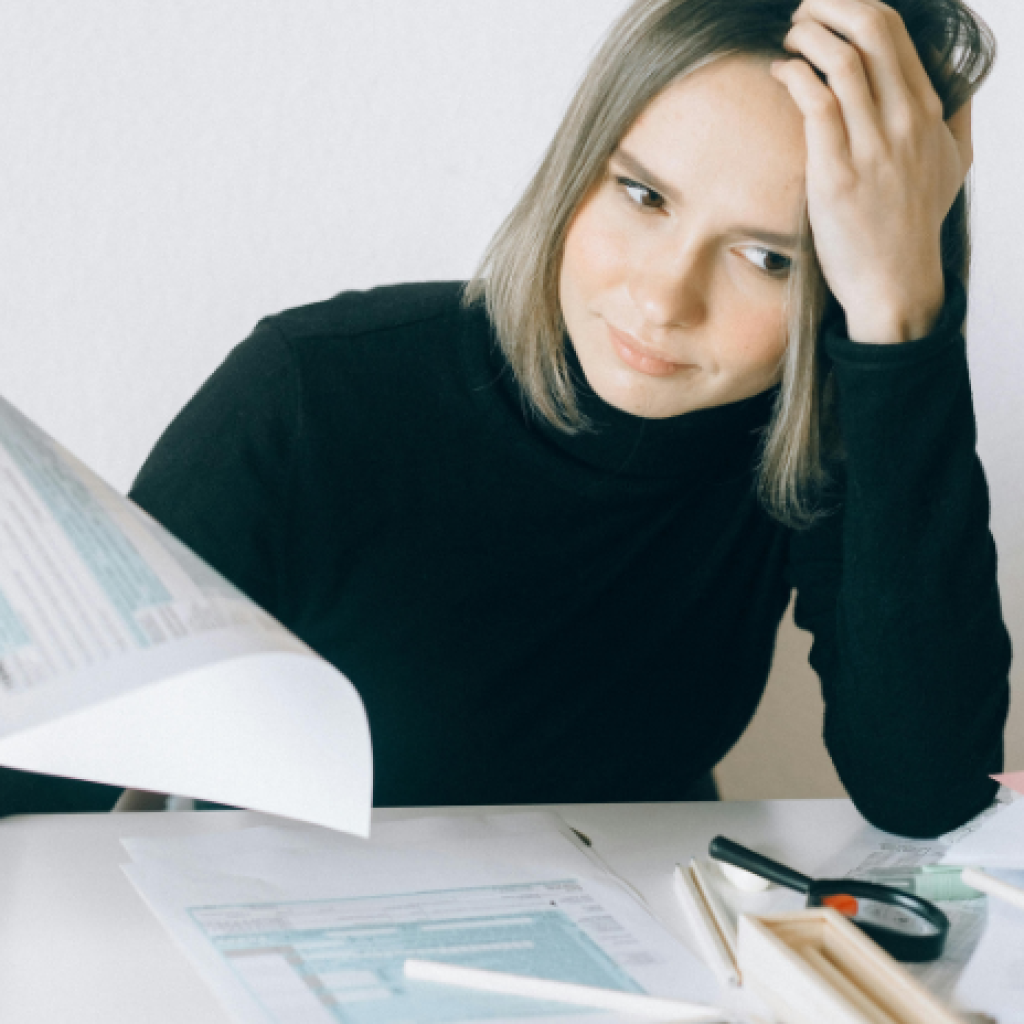 A person sitting at a desk sorting through various documents - looking stressed.