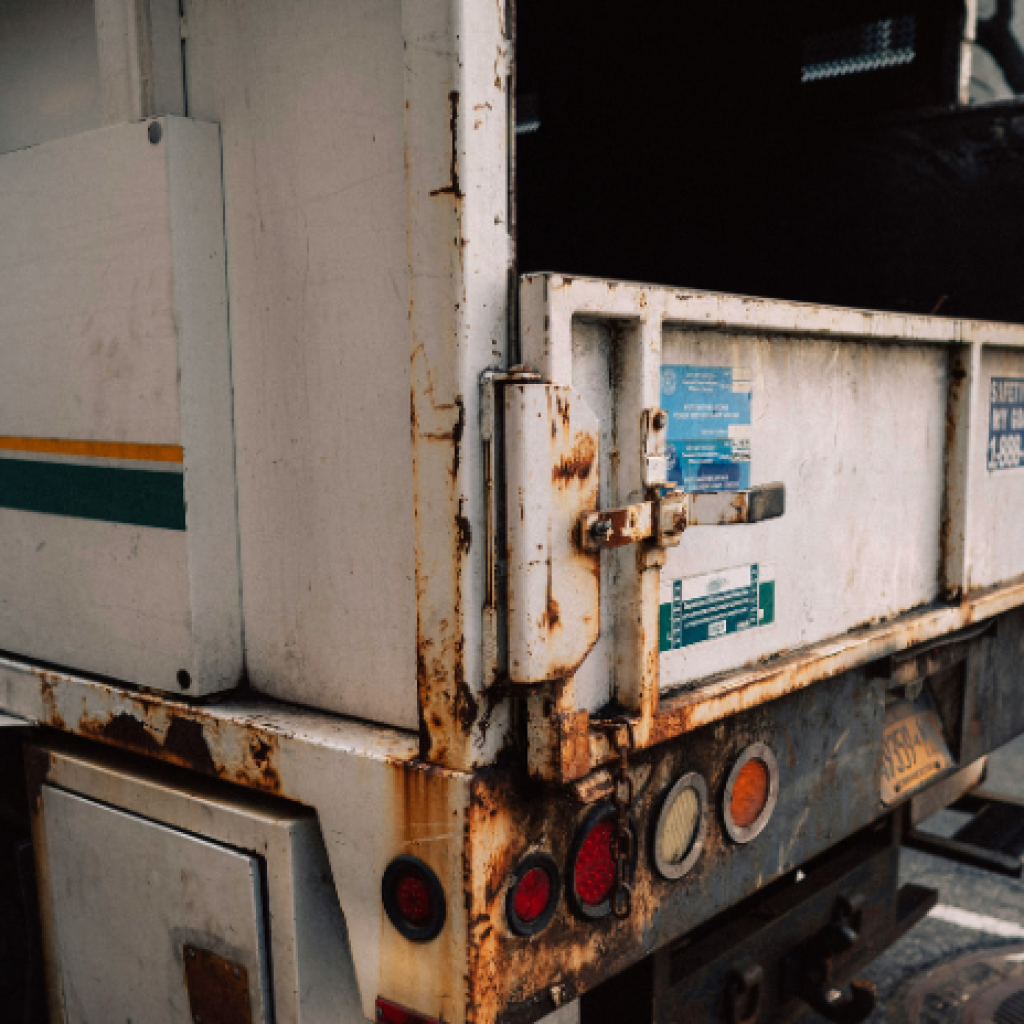 A refuse truck stopped at the side of a busy road