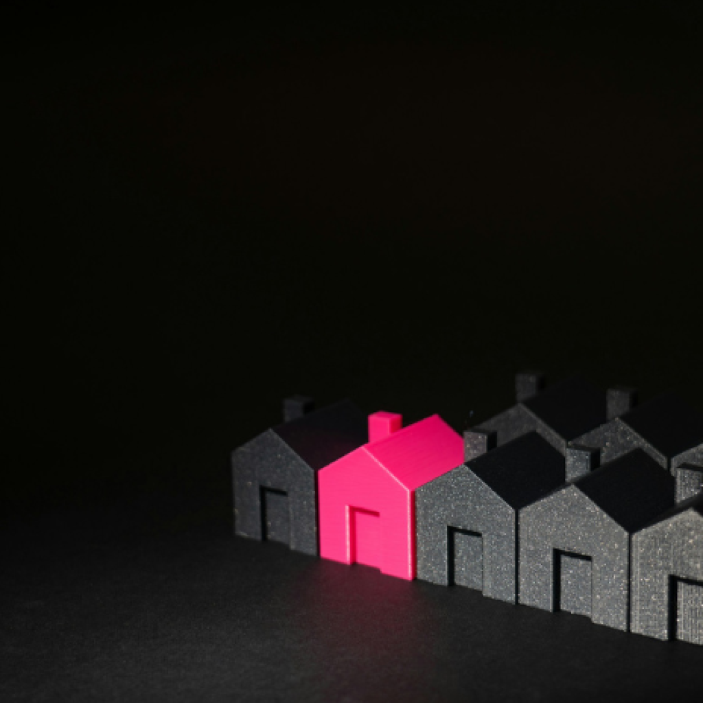 Rows of small mostly black model houses. Two are pink