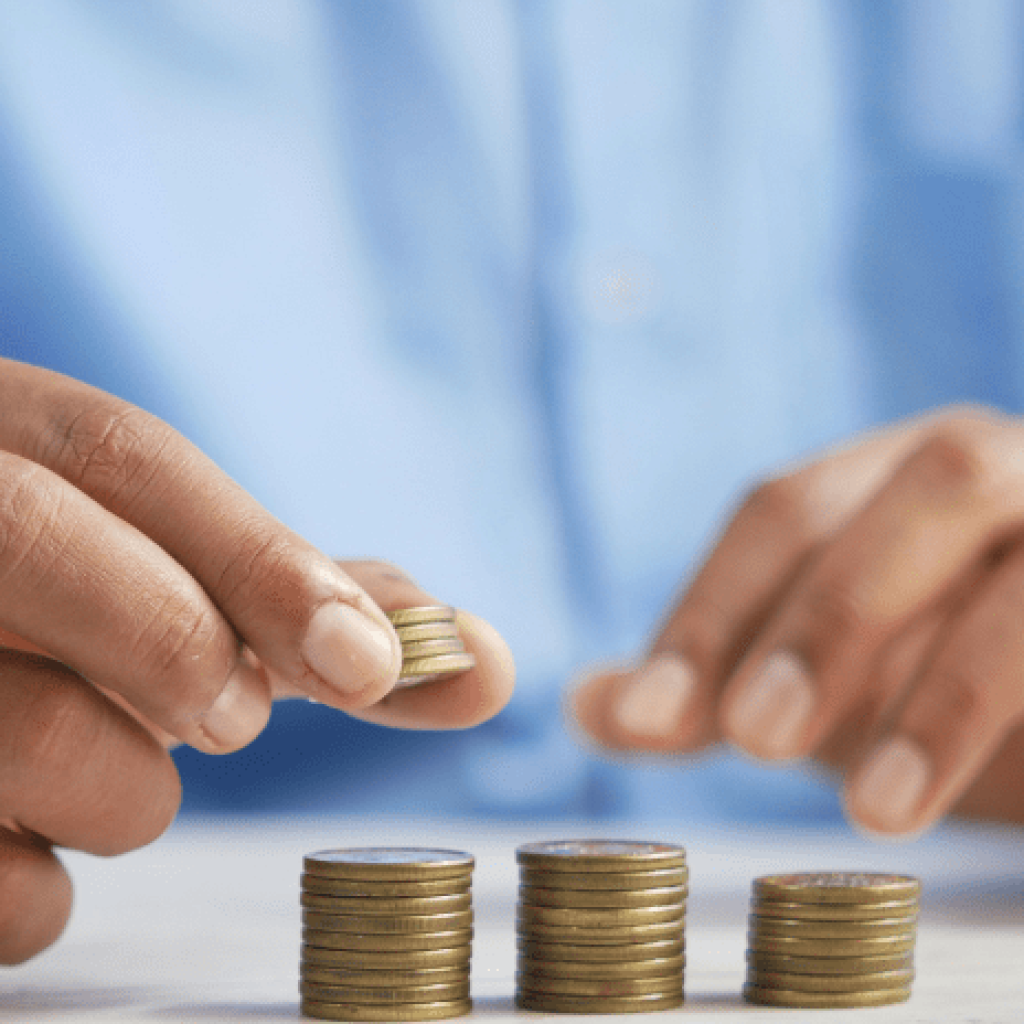 3 stacks of coins with someone adding more to one of the stacks so that each is taller than the last.