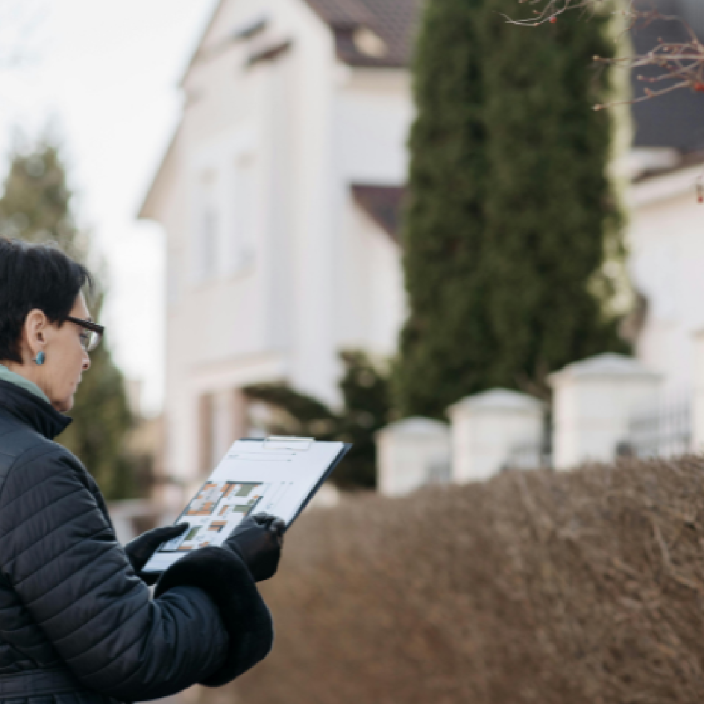 A property assessor consulting a clipboard during an onsite reinstatement cost assessment